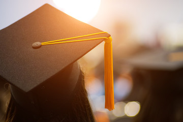 Rear view selective focus of the university graduates crowded in the graduation ceremony. The graduates stand in-line while waiting for  awarding degree certificate. Graduation congratulations