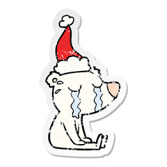 distressed sticker cartoon of a crying sitting polar bear wearing santa hat