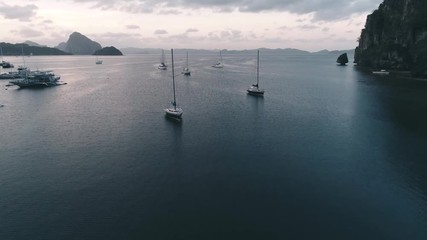 Aerial drone view of boats anchored in the bay with clear and turquoise water on the sunset. Boat and yacht in the tropical lagoon. Tropical landscape. El Nido, Palawan island, Philippines.