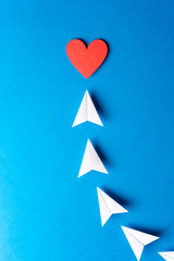 Design love card. Paper origami white airplanes with red heart shape with copy space on blue background. Social media, sharing and send concept.