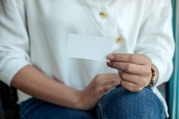 A woman holding and showing a blank empty business card to someone