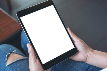 Mockup image of a woman sitting and holding black tablet pc with blank white desktop screen