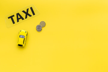 Taxi operator concept. Chip service. Sign taxi ner car toy and coins on yellow background top view...