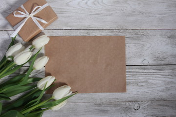 White tulips, gift box and paper card for message on white wooden table. Women day concept. White ribbon, 8 march, spring, frame