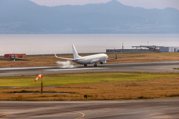 A white airplane landing touch down at Osaka airport, Japan