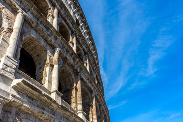 Naklejka premium Facade of the Great Roman Colosseum (Coliseum, Colosseo), also known as the Flavian Amphitheatre. Famous world landmark. Scenic urban landscape.