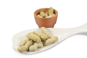 Peanuts on white ladle isolated on white background, red clay pot as background. Clipping path.