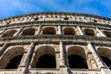 Obraz premium Facade of the Great Roman Colosseum (Coliseum, Colosseo), also known as the Flavian Amphitheatre. Famous world landmark. Scenic urban landscape.
