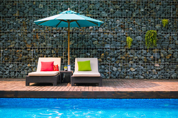 Sunbeds with umbrella near swimming pool on summer vacation.