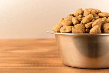 Bowl with dog food on a wooden table. Close up.