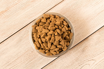 Bowl with dog food on a wooden table. Close up.