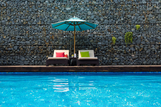 Sunbeds With Umbrella Near Swimming Pool On Summer Vacation.