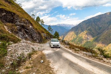 Tourist vehicle on scenic mountain road with distant Himalaya snow peaks and valley near Munsiyari Uttarakhand India.