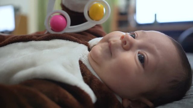 Cute baby boy playing toy. Cute child playing with rattle on bed. Sweet child portrait. Close up of lovely baby face