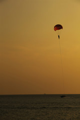 Silhouette of skydiver flies on background of sunset sky and sea 