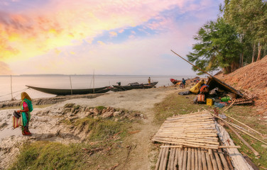 Fototapeta na wymiar Rupnarayan river bank at sunset with view of fishing boats and rural village people at Deulti, West Bengal, India.