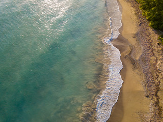 Aerial Drone shot showing the wave breaks on the  golden coloured sand beach