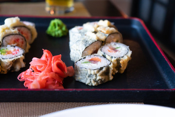 Rolls, ginger and wasabi are on the serving tray. Japanese food in the restaurant.