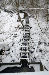 Fish ladder on embankment seen from above. Frost has caused icing on the ladder.