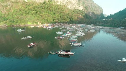 Aerial drone view of boats anchored in the bay with clear and turquoise water. Boat and yacht in the tropical lagoon. Tropical landscape. El Nido, Palawan island, Philippines.