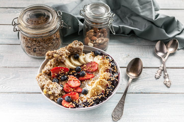Organic breakfast. Healthy breakfast bowl: Cottage cheese, granola, bananas, strawberries, blueberries and puffed rice. Wooden table background