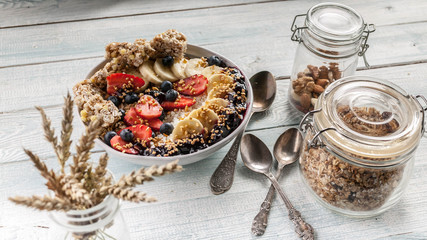 Organic breakfast. Healthy breakfast bowl: Cottage cheese, granola, bananas, strawberries, blueberries and puffed rice. Wooden table background
