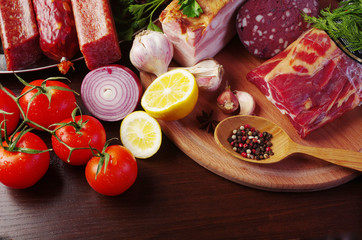 Meat products, vegetables and spices on the kitchen board.