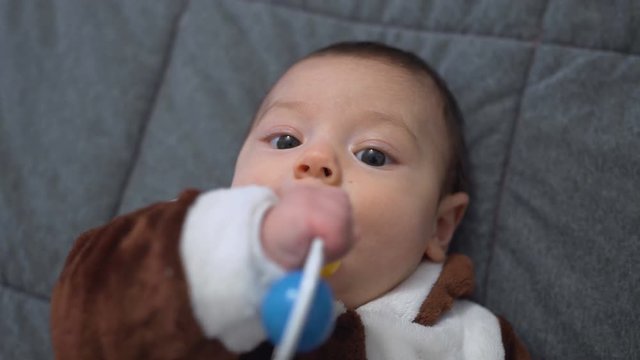 Cute baby boy playing toy. Cute child playing with rattle on bed. Sweet child portrait. Close up of lovely baby face