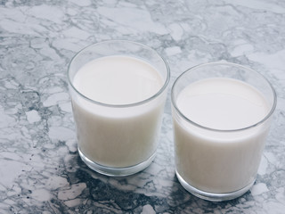 Pouring milk in the glass on blue background. Fresh milk pouring making a crown splash. Front view. Milk glass top view. Natural ingredients concept. Tasty healthy products on a table,selective focus.