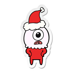 sticker cartoon of a cyclops alien spaceman wearing santa hat