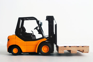 toy yellow orange forklift truck from side driving and lifting a pellet. Isolated on white background