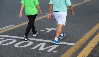 Image of Asian man and woman walking in jogging track in public park in twilight evening.