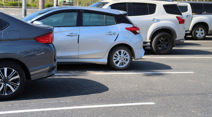 Closeup of back or rear side of blue car and other cars parking in outdoor parking area in bright sunny day. 