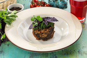 Baked eggplant with basil on top on blue wooden table