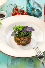 Baked eggplant with basil on top on blue wooden table