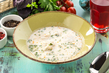 plate of white fish soup on blue wooden table
