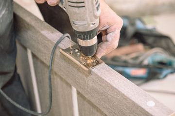 To fasten the hinge. The man fastens the hinge. Twist the hinges on the door. Installation of door hinges. Door installation.