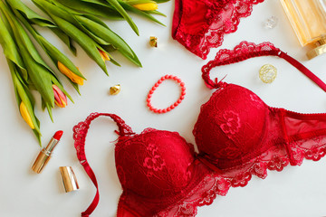 Red women underwear and spring Tulips flowers on white. Red bra and pantie. Copy space. Beauty, fashion blogger concept. Romantic lingerie for Valentine's day temptation.Erotic concept.Floral pattern.