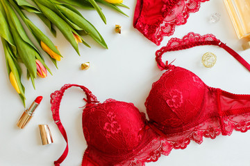 Red women underwear and spring Tulips flowers on white. Red bra and pantie. Copy space. Beauty, fashion blogger concept. Romantic lingerie for Valentine's day temptation.Erotic concept.Floral pattern.