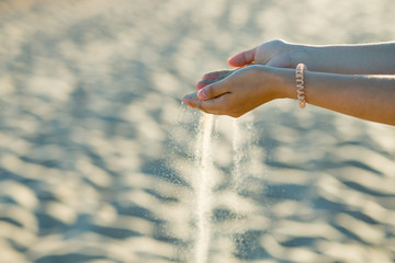 Beautiful girl hands scatter the sand on the beach. Concept - time is running out, nothing lasts...