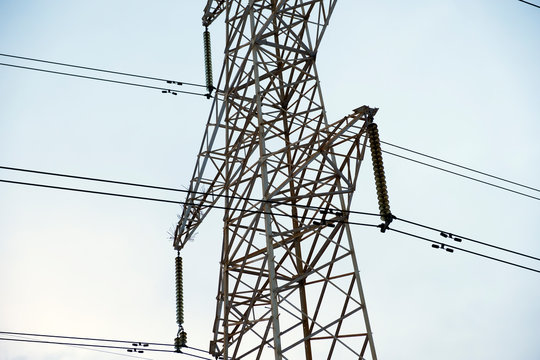 Power lines with many wires and metal supports on the open water against the sky