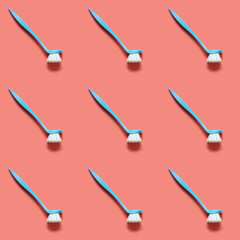 Pale blue brush for washing dishes lying on living coral background. In the style of pop art. Top view. Copy space.
