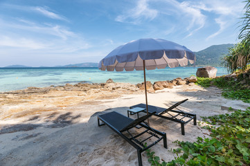 Umbrella with wooden sunbed on the white beach at tropical sea