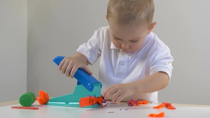 A two years old preschool child playing with modeling clay (compound). Smiling and looking at the camera. Early childhood education to children concept