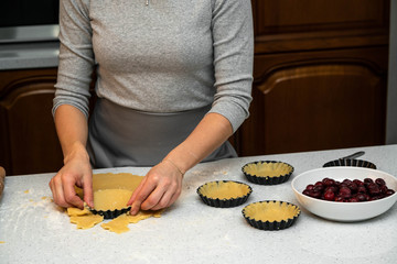 female making tartlets, working with hands on the marble kitchen surface