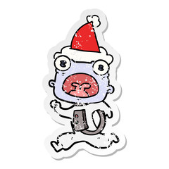 distressed sticker cartoon of a weird alien running away wearing santa hat