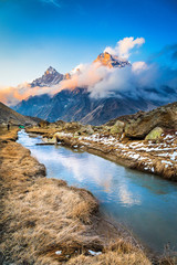 Tapovan during a colorful sunset with clouds floating across the valley and clear blue Akash Ganga river flowing down the valley © Nitish