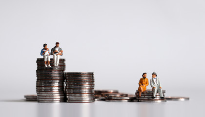 Coins and miniature people. The concept of a generational economic gap.