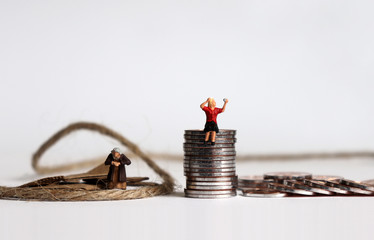 Coins with miniature people. The concept of people spending their old age in poverty.