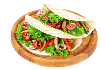 Tortilla wrap with fried chicken meat and vegetables on wooden board isolated on white background